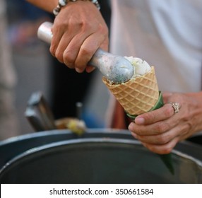  hand with ice cream scoop on cones , Thailand ,Vanilla ice cream scoop, scooped out of a container with a utensil