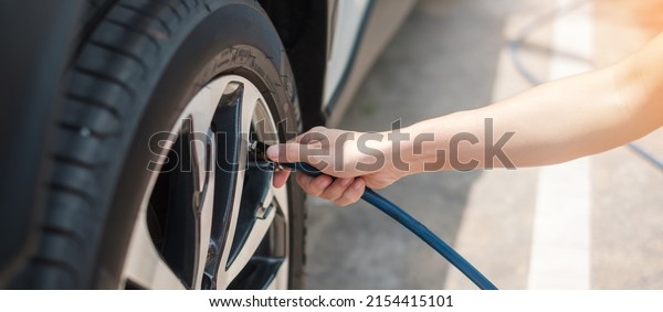 hand inflating tires of vehicle,\
checking air pressure and filling air on car wheel at gas station.\
self service, maintenance and safety transportation\
concept