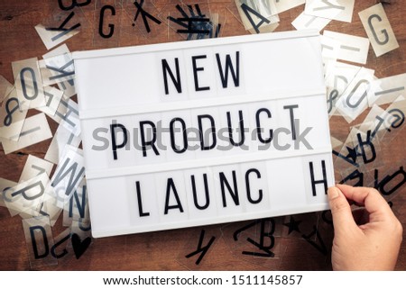 Hand insert plastic alphabets on advertising lightbox on the table, New Product Launch text for business concept