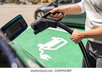 Hand inserting a DC CCS2 EV charging plug into electric car socket at charging station, Hypercharger or Supercharger.  Charge electromobility concept image.