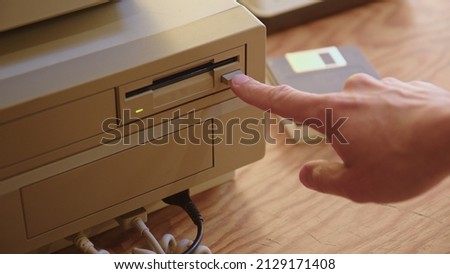 Hand inserting and ejecting Floppy Disk into vintage Commodore Amiga 2000 PC. Popular Gaming PC in the 80s and 90s.