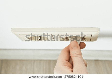 Hand inserting an electric plug into an electrical outlet for energy