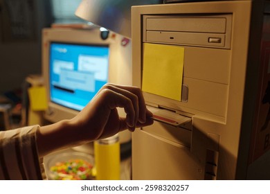 Hand inserting floppy disk into vintage computer with background showing another computer monitor displaying a blue screen. Scene capturing nostalgia of retro technology