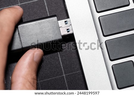 Hand inserting Hardware Wallet plugged into a computer laptop.