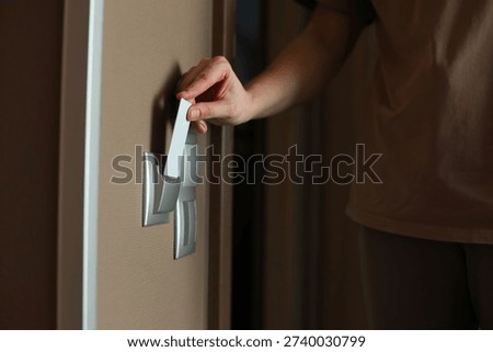 Hand inserting key card into hotel room power switch, activating lights, signaling occupancy or housekeeping access in modern accommodation.