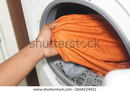 Hand inserting laundry into a dryer during household chores