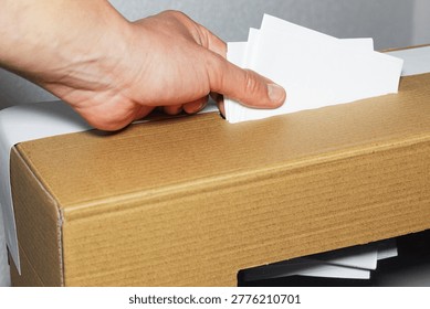 A hand inserting multiple ballots into a ballot box, manual voting and electoral crime
