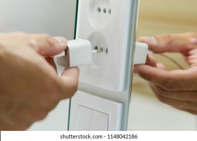 Hand inserting unplug or plugged electrical plug into outlet