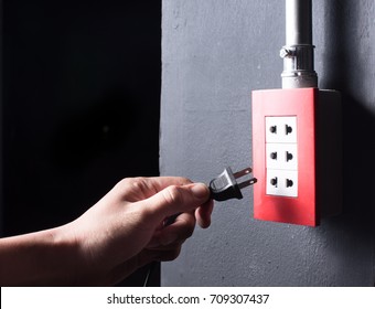 Hand Inserting Unplug Or Plugged Electrical Plug Into Outlet Over Dark Background