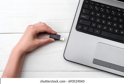 Inserción manual de la unidad flash USB en el equipo portátil con fondo blanco. Cierre de la plugometría de enchufe manual de mujer en el portátil en casa. Copia de datos de la unidad flash al equipo portátil