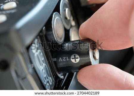 Hand inserts 1.2V battery into electronic device compartment, highlighting correct polarity and concept of portable power for everyday technology