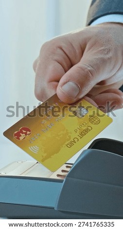A hand inserts a gold Mastercard with a chip into a payment terminal, emphasizing secure, contactless transactions. This scene captures modern banking and finance, reflecting the convenience.