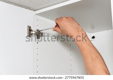 Hand installing hinge inside cabinet. High quality photo