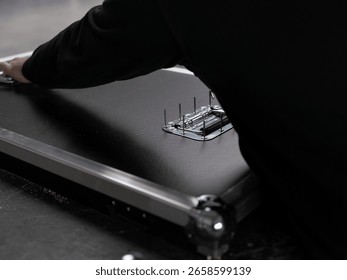 Hand installing precision hardware component on dark surface during flight case manufacturing assembly