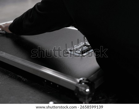 Hand installing precision hardware component on dark surface during flight case manufacturing assembly