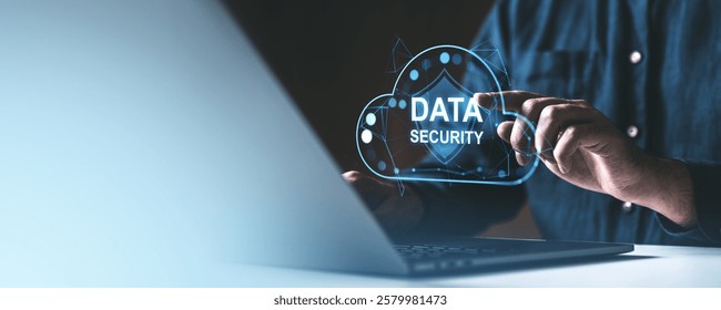 Hand interacting with holographic cloud-shaped shield reading Data Security above a laptop on a gradient background. Represents cybersecurity
