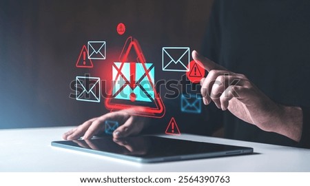 A hand interacting with a tablet showing red warning icons and email symbols on a dark background, symbolizing email spam alerts
