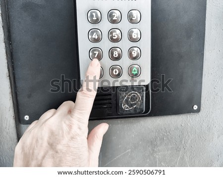 Hand interacts with elevator intercom buttons, specifically selecting button in a residential building.