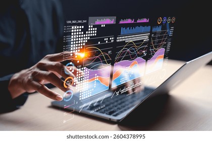 A hand interacts with holographic data visuals above a laptop, showcasing modern technology and data analysis.