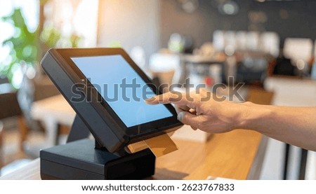 A hand interacts with a touchscreen POS system in a cafe setting. The device displays a blank screen, ready for transaction processing. A card reader is visible.