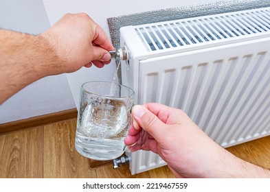 Hand with a key for draining drains water and air from the heater in a cup. Adjust heating system, preparing the house for the new cold autumn or winter season. Bleed valve in heating radiator.
