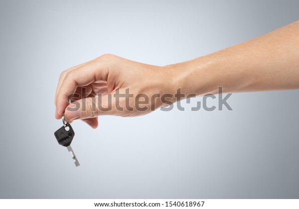 Hand with a key on gray\
background