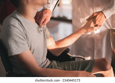 Hand of a kind doctor checking heartbeat to young man with disability in examination room, Activity in hospital ,home,quarantine,Symptom monitoring and consultation by a specialist,Healthcare concept. - Powered by Shutterstock