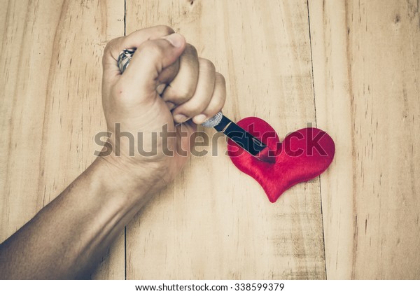 hand with a knife\
stabbing into a red heart 