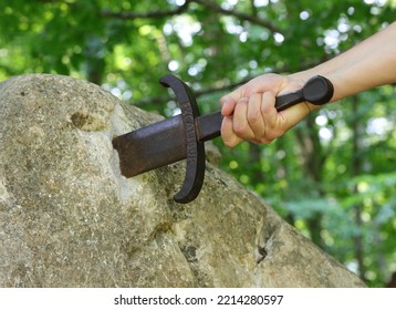 Hand Of The Knight Who Tries To Extract The Excalibur Sword Stuck In The Rock In The Middle Of The Enchanted Forest