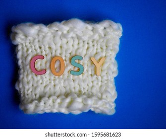 Hand Knit Coffee Cosy With The Word Cosy On Top In Multi Colored Wooden Letters