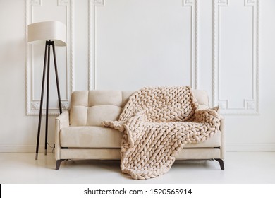 Hand Knitted Merino Wool Chunky Blanket In Interior On Background. Stylish And Cozy Scandinavian Interior: Bed, Chair, White Wall.