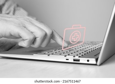 Hand At Laptop Keyboard And Virtual First Aid Kit. Man Searching Information About Urgent Medical Care Or List Of Necessary Contents Or Ordering Medicine Online. Health Care Concept. Photo