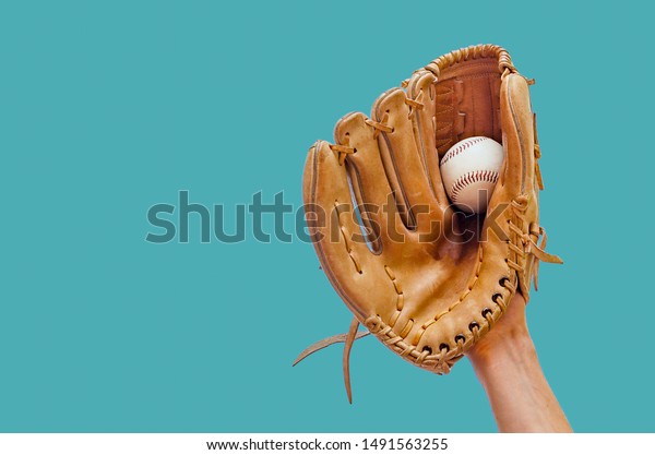 Hand in a leather baseball glove caught a ball\
on a green background