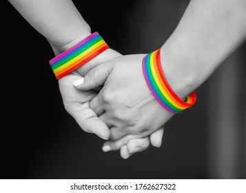 Hand Of LGBT Women Holding Together With Rainbow Ribbon Symbol; Concept Of LGBT Pride, LGBTQ People, Lgbt Rights Campaign. BLACK AND WHITE PHOTO 