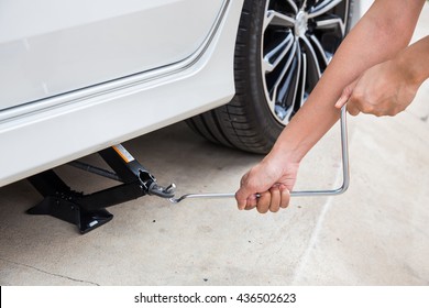 Hand lifting a car with spanner jack-screw