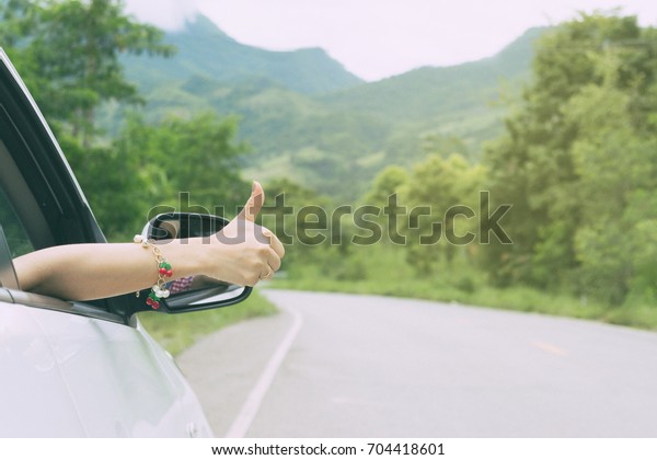 Hand like thumbs car on the road with trees along\
the way travel