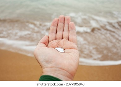 hand with liquid mercury in the palm of the hand with the sea in the background. Liquid mercury concept. dangerous chemical element