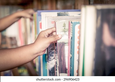 Hand Of Little Girl Selecting A Book From Book Shelf In Vintage Color Tone