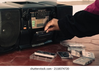 Hand loading an audio cassette tape into a tape recorder from the 90s