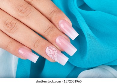 Hand and long artificial manicured nails and ombre gradient design in pink   white colors