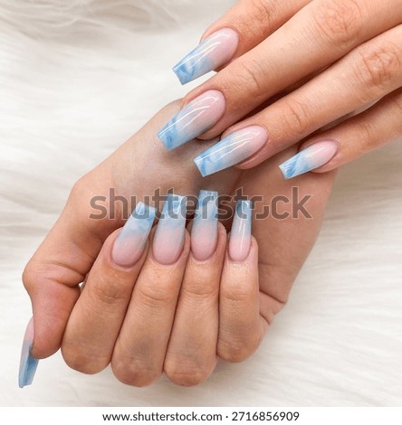 Model’s hand with long square nails featuring blue marble ombre designs