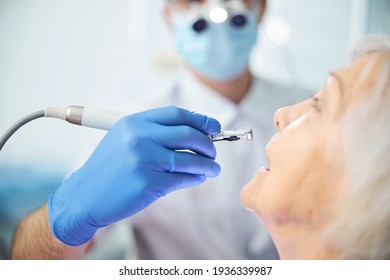 Hand lowering dental handpiece with bur to pensioner teeth