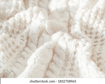 Hand made cable-knit sweater sweater. Texture of warm knitted fabric with pattern. White crumpled cardigan. Cozy autumn outfit for snuggle weather.