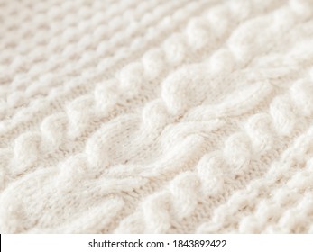 Hand made cable-knit sweater sweater. Texture of warm knitted fabric with pattern. White cardigan. Cozy autumn outfit for snuggle weather.