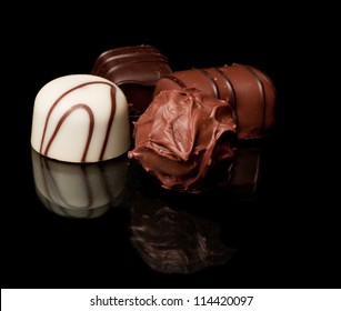 Hand Made Chocolates On A Reflective Black Surface Different Colors And Shapes