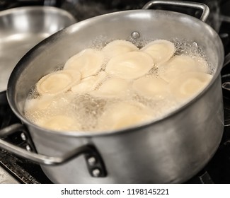 Hand made ravioli simmering in a pot of boiling water on the stove.