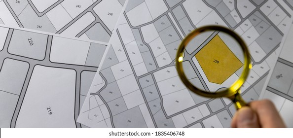hand with magnifier on cadastre map - search and buy land concept. banner copy space