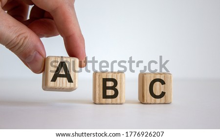 Hand making a choice between cubes with leteres A, B and C on beautiful white background. Business concept. Copy space.