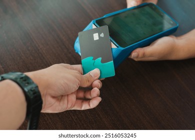 A hand making a contactless payment using a debit or credit card on an electronic data capture device or EDC