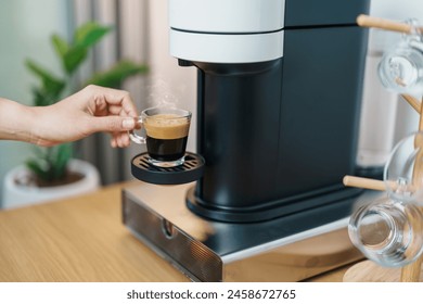 hand making Espresso Coffee by Coffee Maker Machine with Capsule of roasted coffee bean on wood table bar. Daily beverage drink at Home, Apartment and Office concept - Powered by Shutterstock